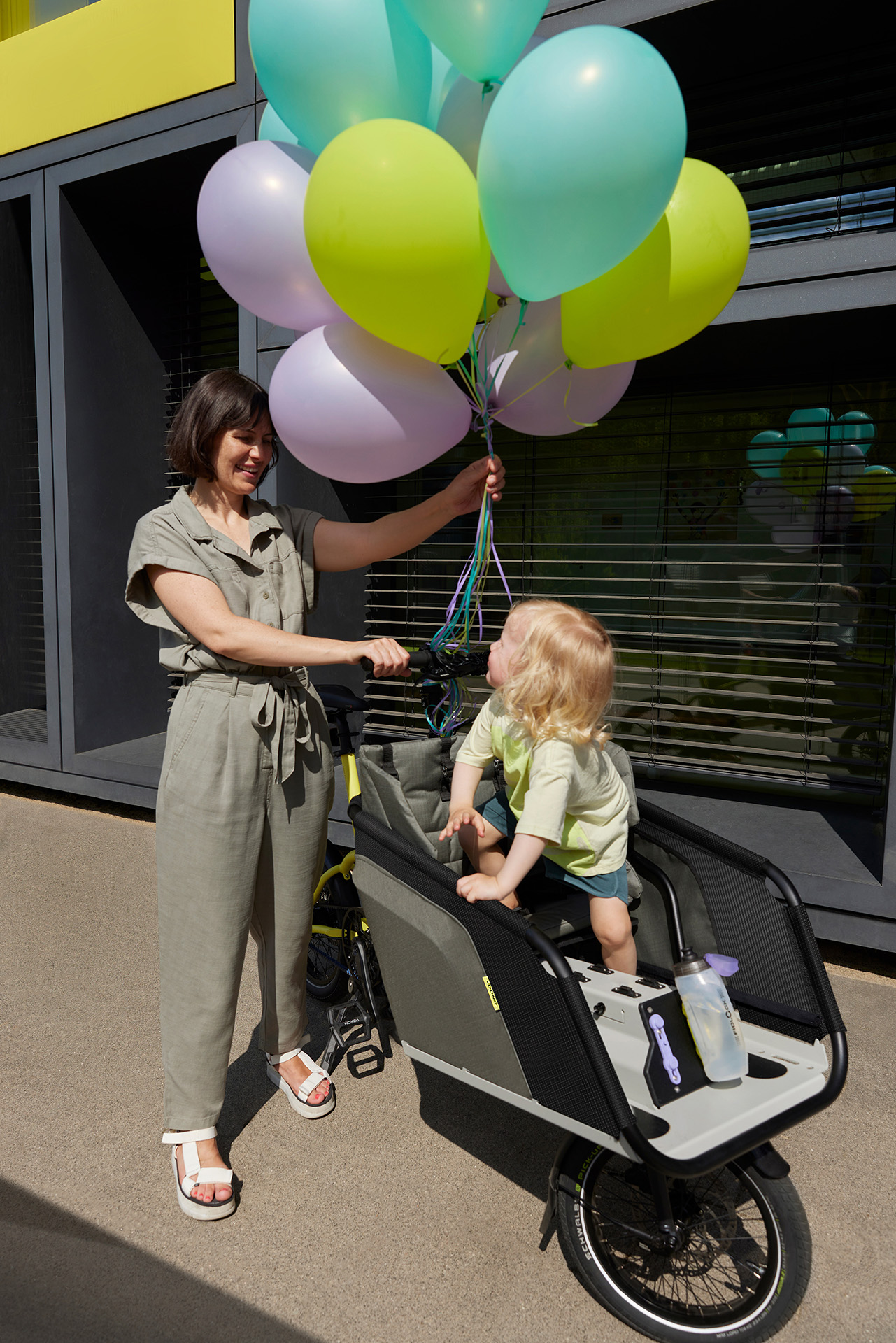 Lastenrad mit Kind und Luftballons