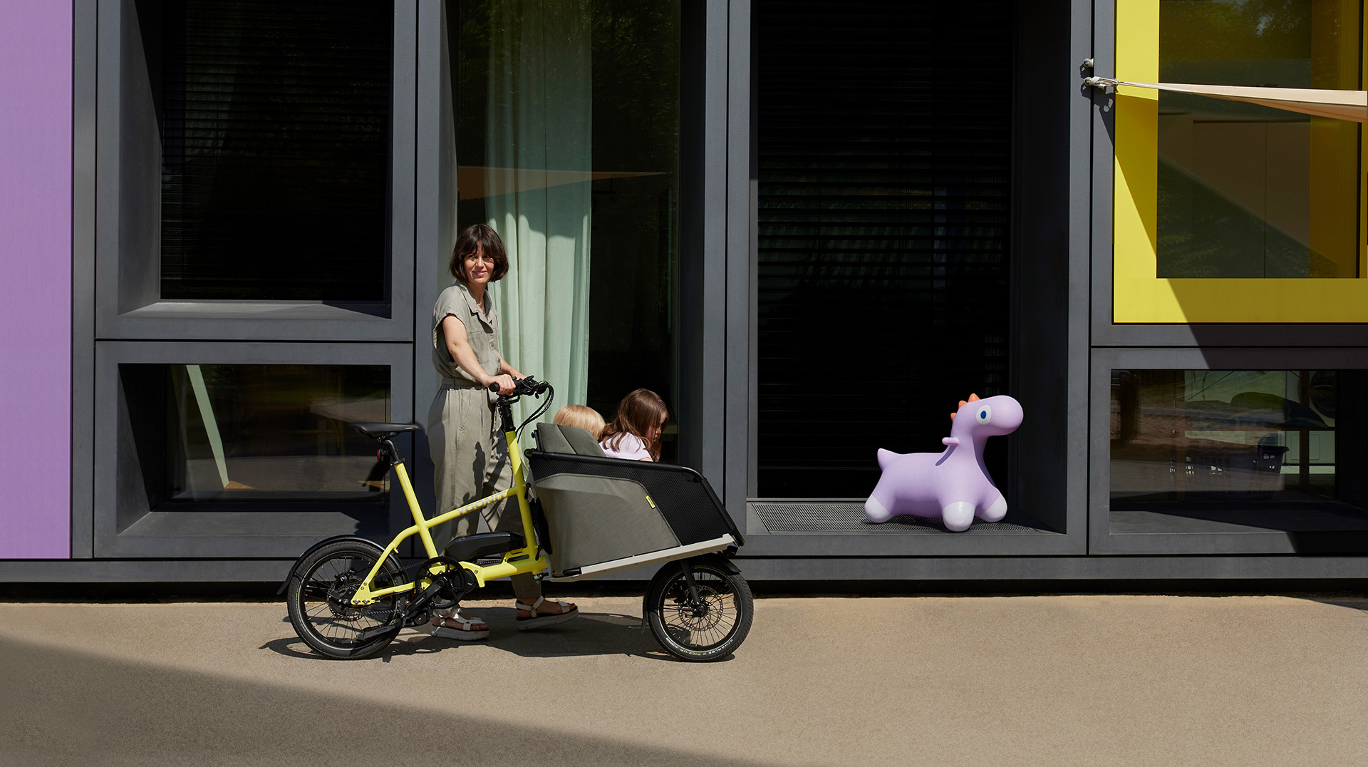 Gelbes Lastenrad vor modernem Gebäude